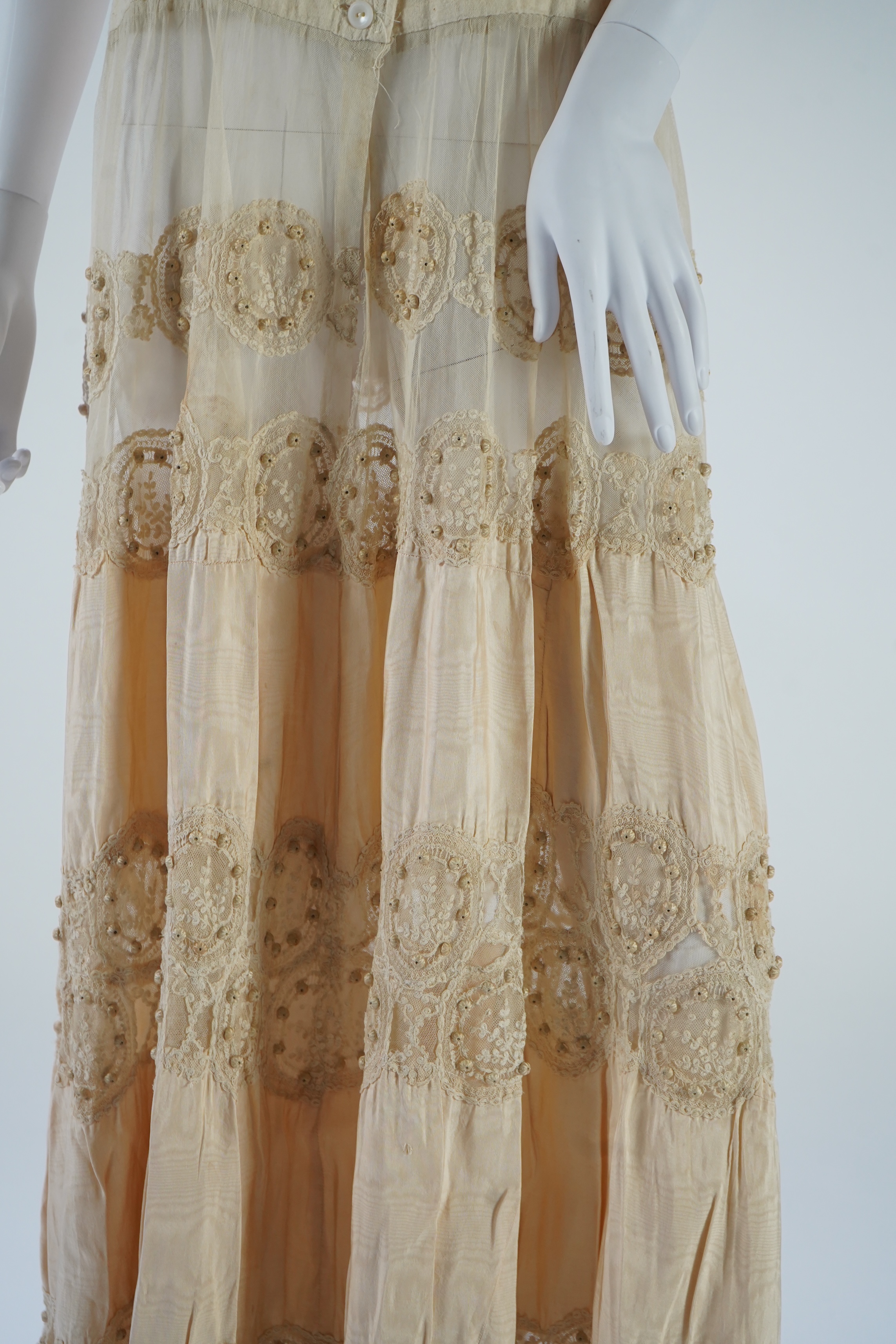 A suitcase containing a cream silk lace skirt to a dress, an Edwardian silk petticoat and various collars, possibly for theatrical use, silk petticoat 96 cm long. Condition - fair